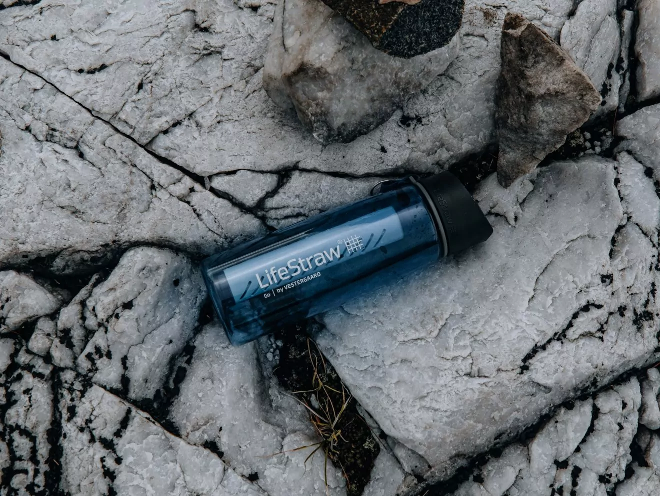 Lifestraw water bottle lying on rocks for water filtration while hiking
