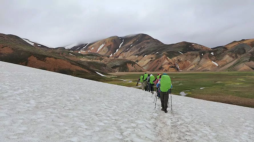 Hikers walking over ice with mountains in background