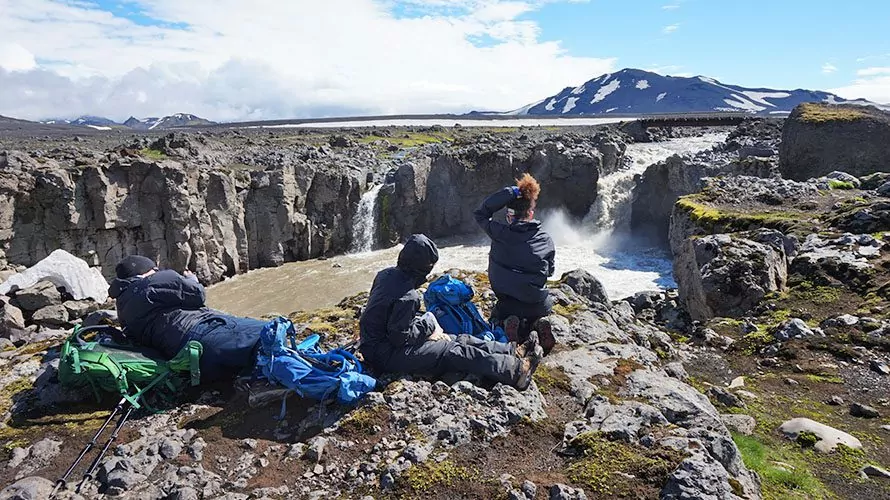 Hikers sitting on rocks looking at waterfall