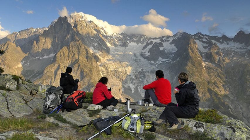 Four hikers eating while looking at a mountain view