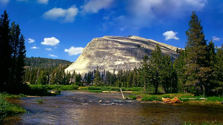 Incredible stone mountain behind river and lush green