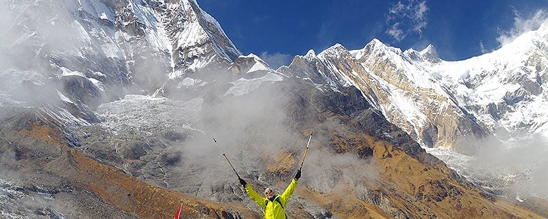 Hiker holding up walking poles near mountain