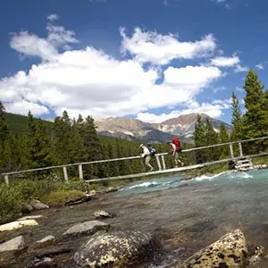 hikers crossing a river on suspension bridge