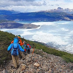 hikers descending rocky path toward cold sea