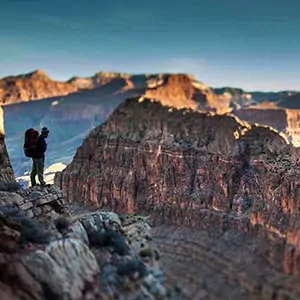 Shadowed backpacker looks out into the depths of the Grand Canyon 