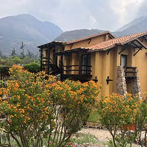 A mustard yellow home sits on the hillside of the Peruvian mountains.