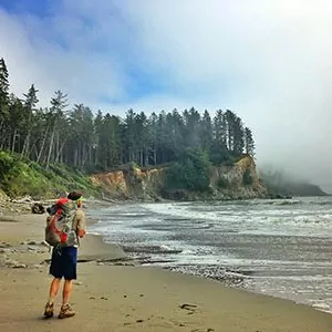 A backpacker hiker enjoys the view of the pacific ocean along the coast of the olympic national park