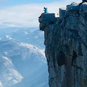 A hiker sits atop an iconic overlook in yosemite national park