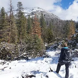 A snowshoer looks towards the summit on a snowy hike.