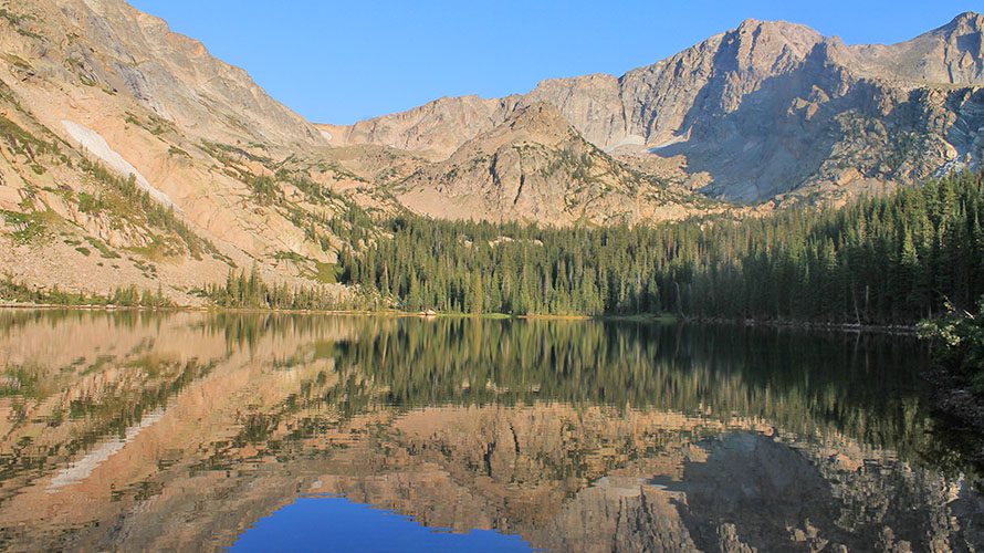 Water reflections of limitless rock climbing potential in Rocky Mountain National Park on an alpine lake