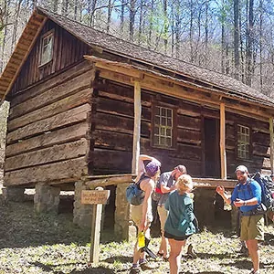 A family discusses their day trip outside a rustic cabin in the Great Smoky Mountains