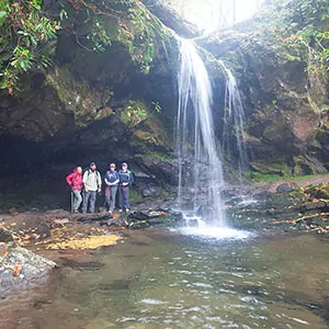 Hikers pose next to a waterfall along their hike in the Great Smoky Mountains