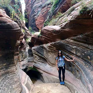 a hiker poses in a slot canyon in zion