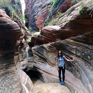 a hiker poses in a slot canyon in zion national park