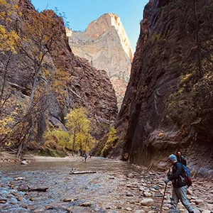 A hiker crosses a riverbed in Zion