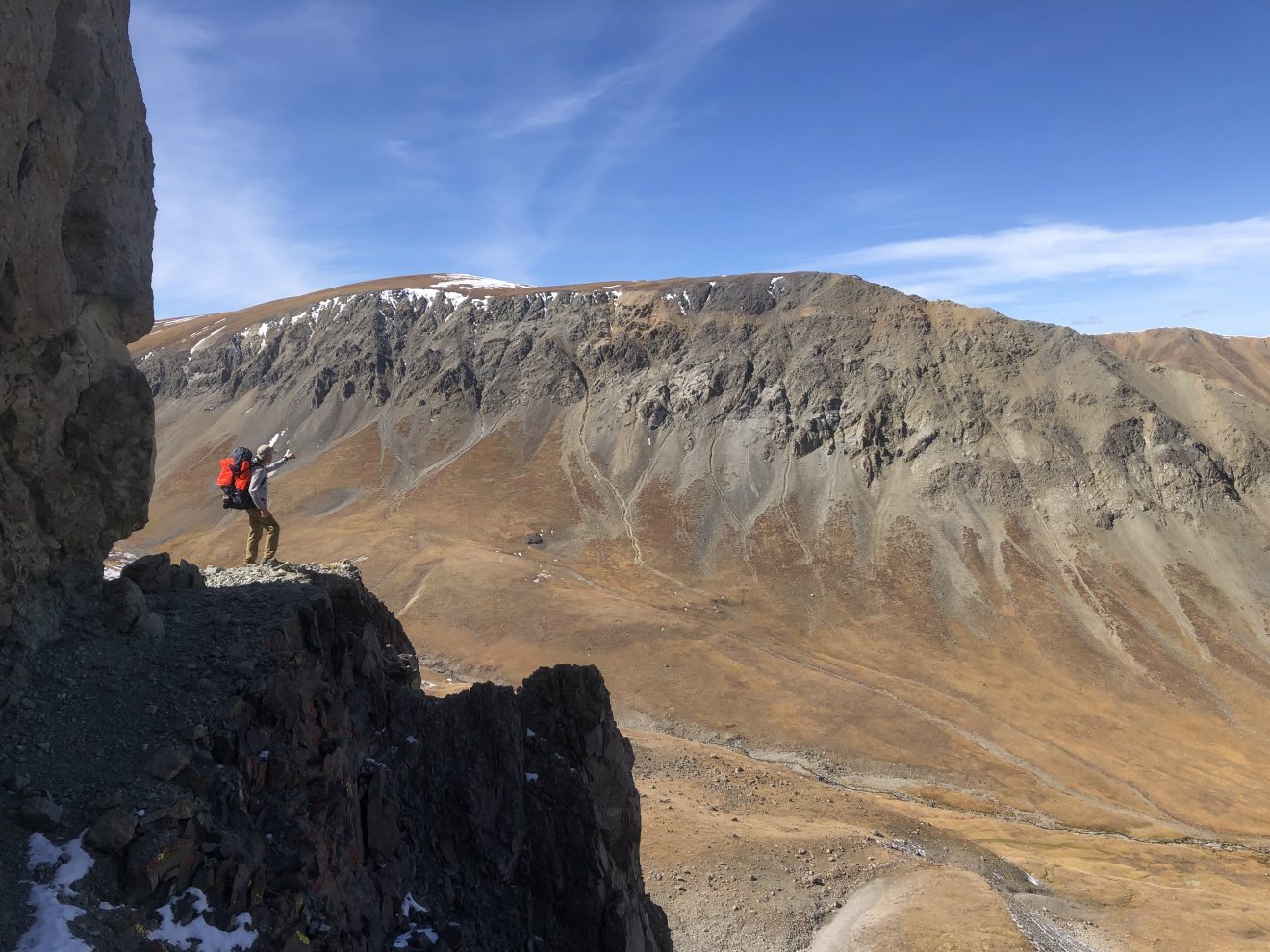 A hiker stands at a precipice at Greybull Pass in the Absaroka Range on the border of Montana and Wyoming.