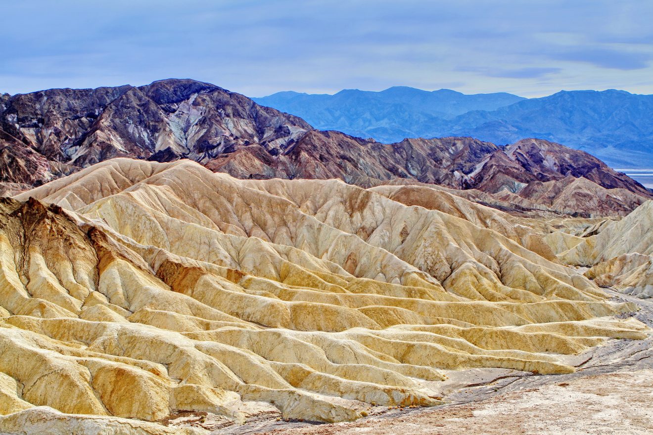 Striated dunes with a blue horizon backdrop in Death Valley National Park. 