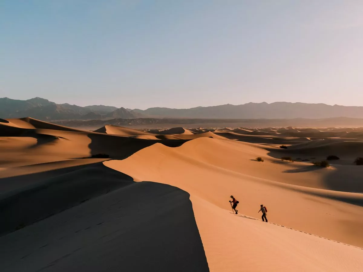 Two hikers hike up the sand dunes in Death Valley National Park