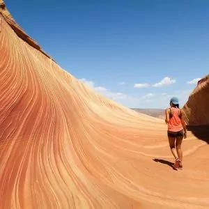 Waves of sandstone rock provide a hiker with a spectacular view on a blue bird day.
