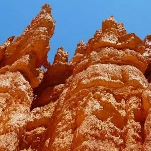 Looking up at sandstone hoodoos with blue skies.