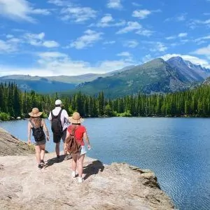 Hikers approach an alpine lake on a summer day in Rocky Mountain National Park