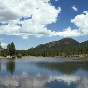 Clouds cover the blue skies at a lake in Rocky Mountain National Park