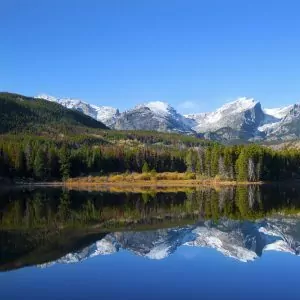 Snowcapped mountains are reflected in an alpine lake in Rocky Mountain National Park
