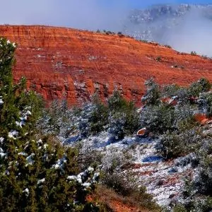 A light snow sits atop the red rock and flora of the desert in Sedona