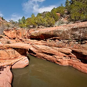 A body of water sits under the red rocks of the desert in Sedona
