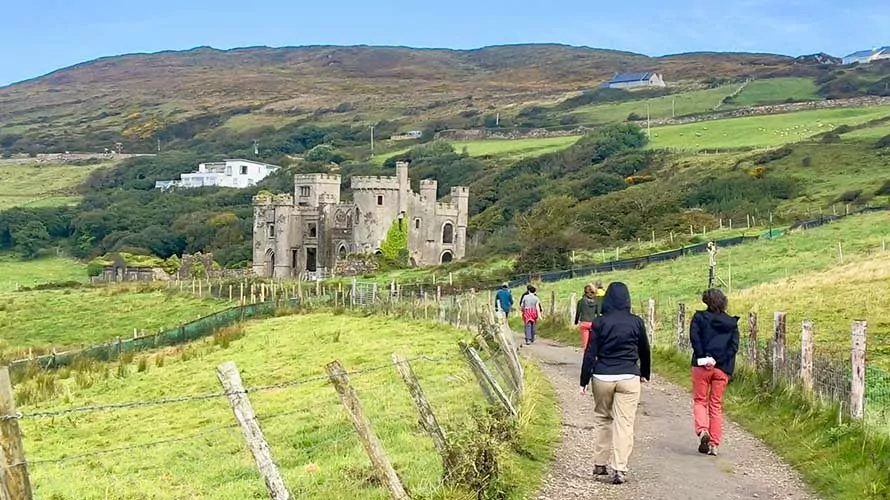 Hikers walking toward an ancient castle in Ireland