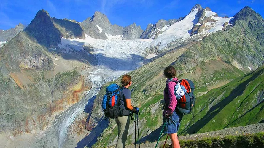 Two hikers looking up at a glacier on the Tour du Mont Blanc Trek