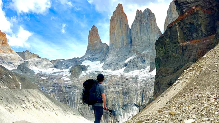 Wildland Trekking hiker standing near glacial lake with granite spires of Torres del Paine