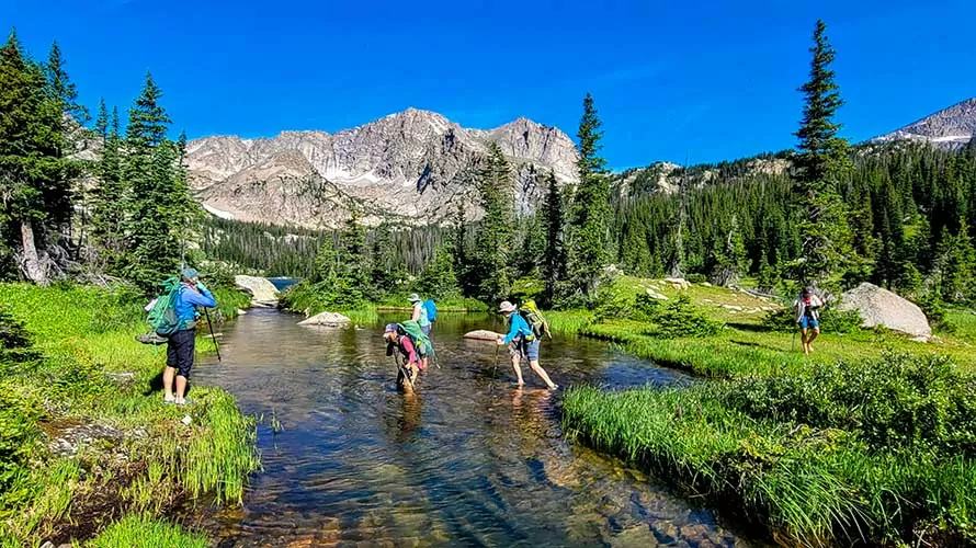Hikers crossing a creek on the Thunder Lake trip with Wildland Trekking