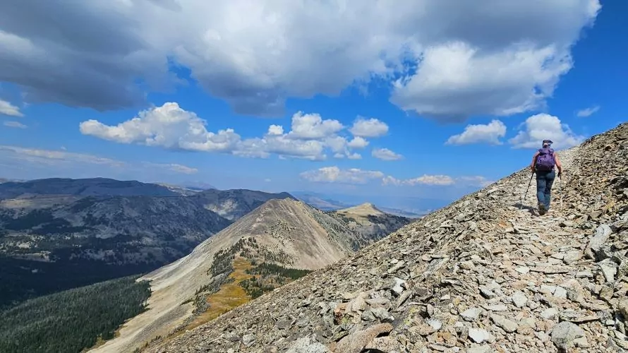 A woman hikes on a treeless mountain ridge line