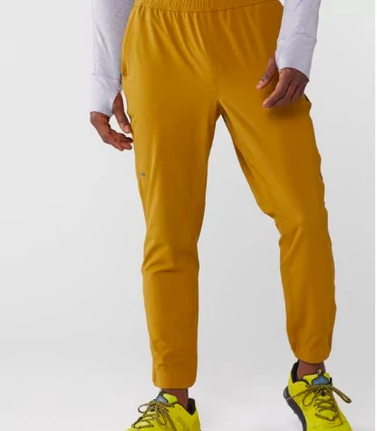 Janji Transit running pants in the color yellow on a male model 