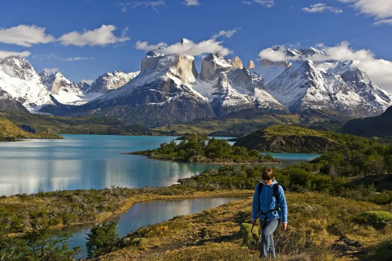 A woman hiker stands in front of the Torres del Paine range in Patagonia
