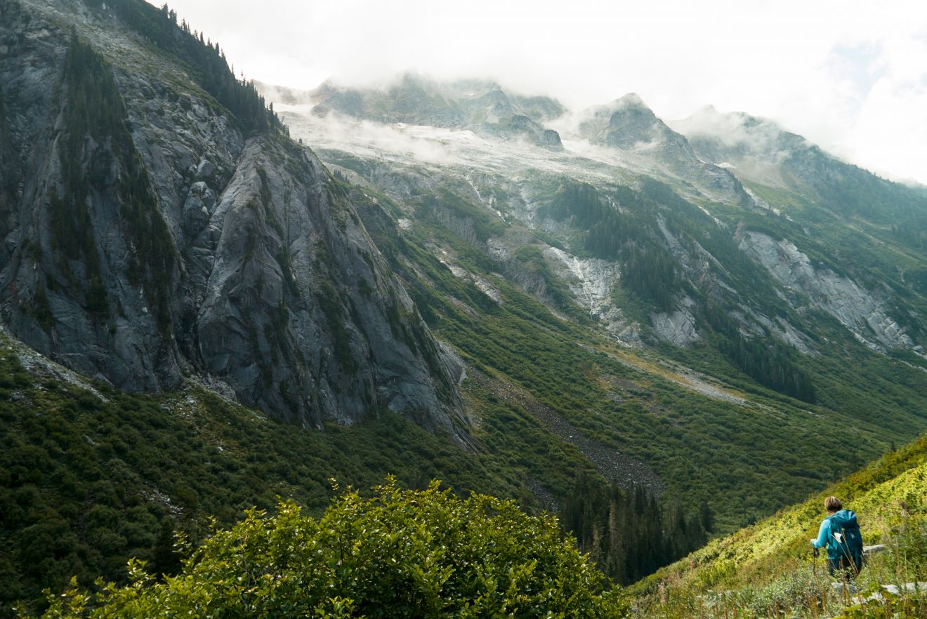 Nooksack Ridge shrouded in clouds with a hiker down in the valley