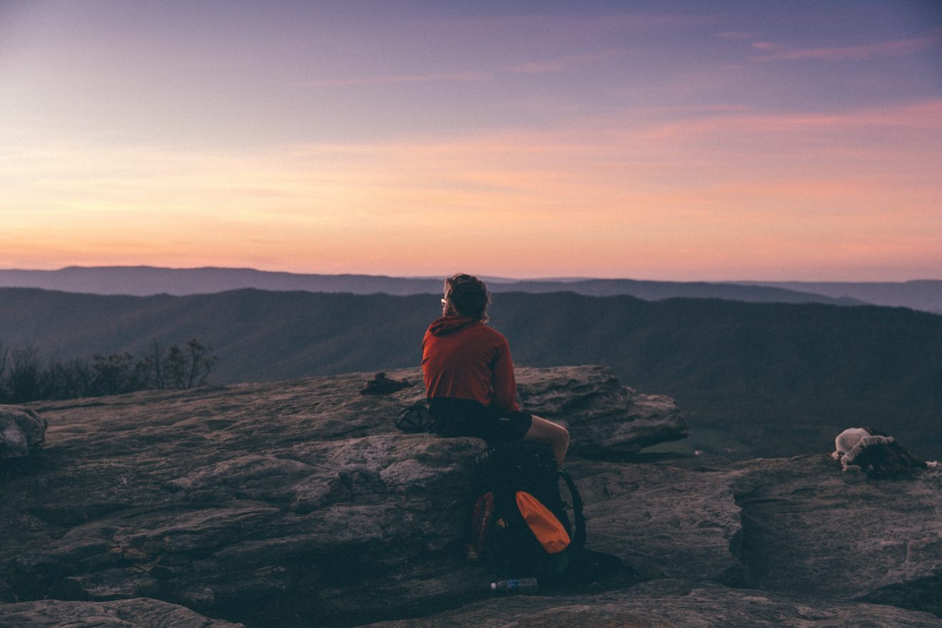 Hiker sits at McAfee Knob at sunrise