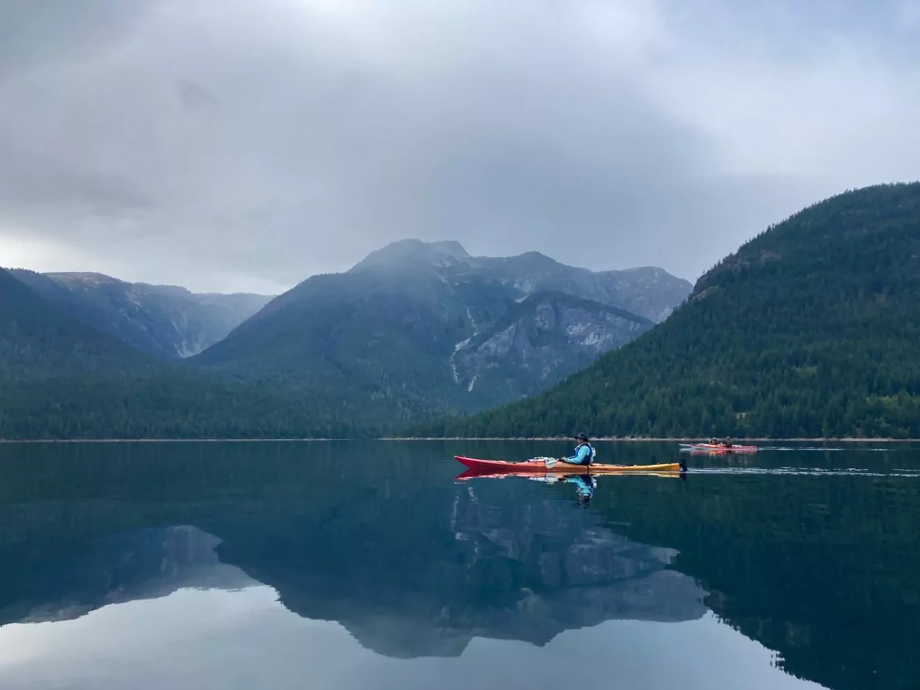 A kayak floats on a cloud-shrewn Ross Lake in North Cascades National Park