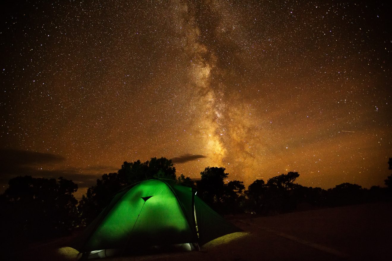 Green tent iluminated under a starry night sky in Canyonlands National park 