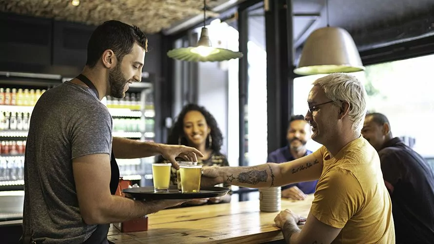 Waiter serving beer to group of friends