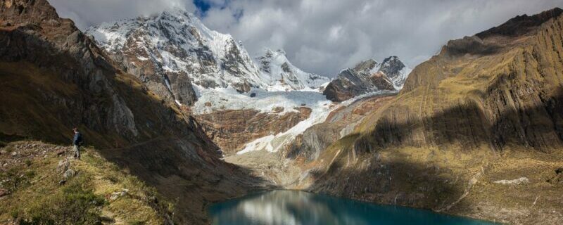 hiker at high alpine lake along huayhuash trek