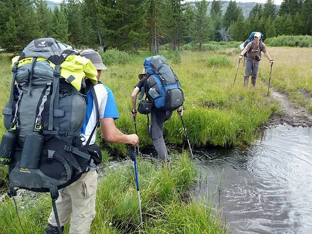 Backpackers crossing water in Yellowstone