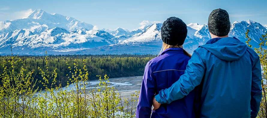 Young couple holding each other and standing in front of mount Denali formerly mount Mckinley, Alaska