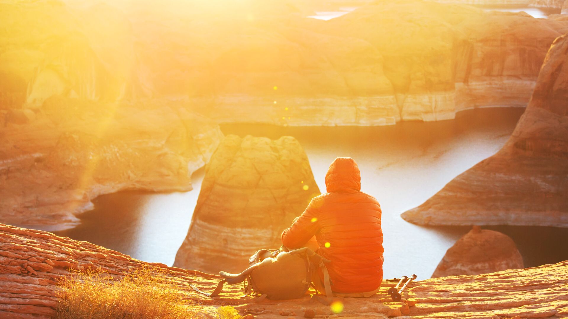 A person sits looking out on the Colorado River and Glen Canyon's Horseshoe Bend