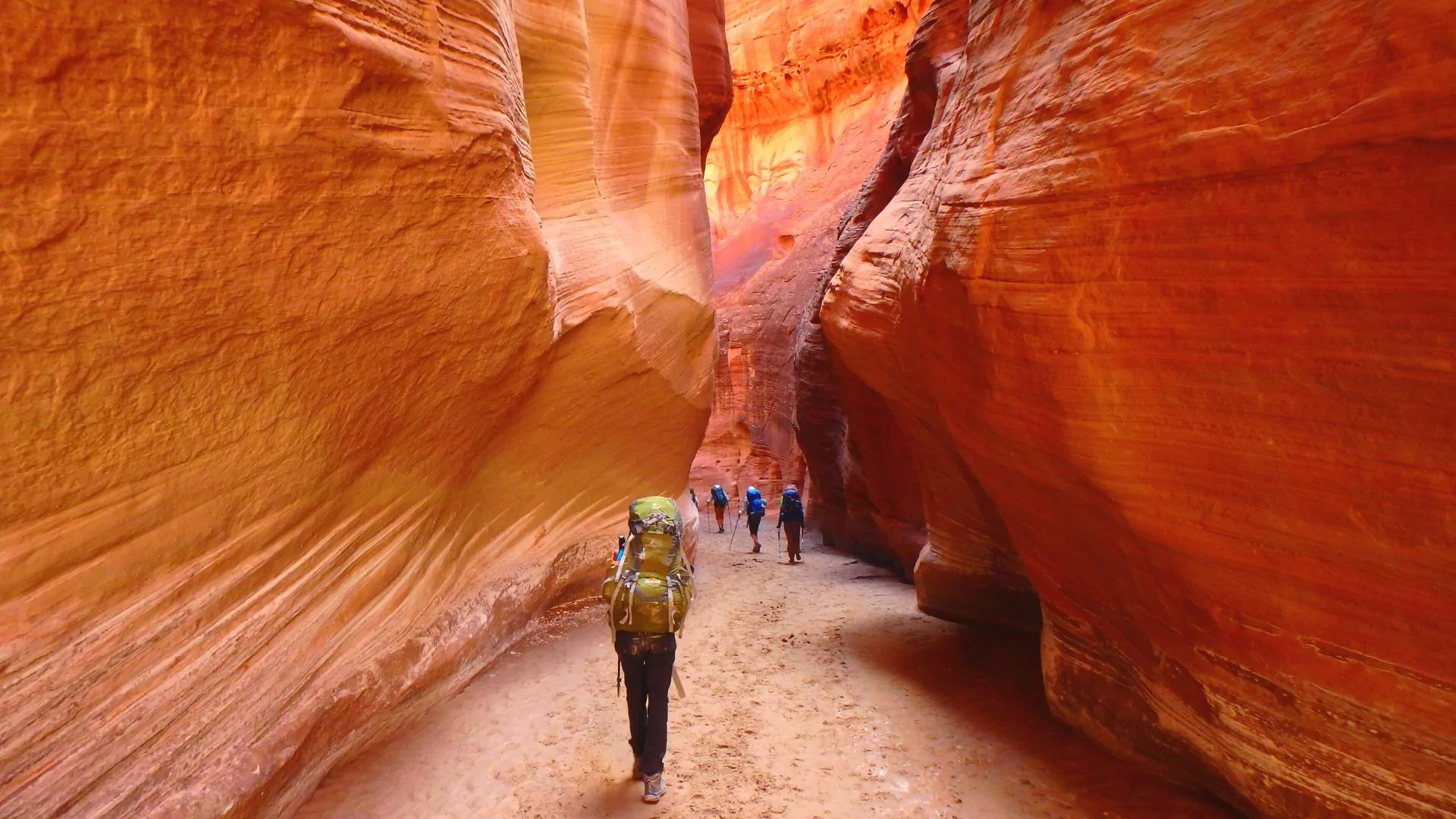 Backpacker walk between narrow red sandstone walls