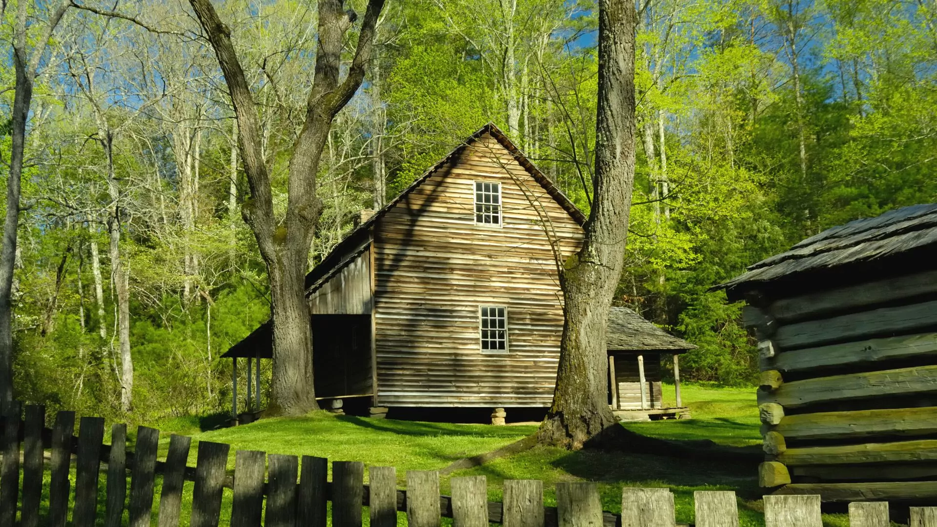 A historic cabin sits among trees just starting to leaf out in early spring