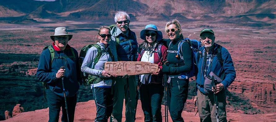 Group of hikers holding Trail Ends sign at Fisher Towers, Utah