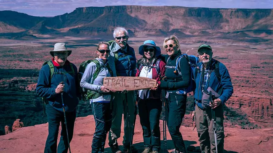 Group of hikers holding Trail Ends sign at Fisher Towers, Utah