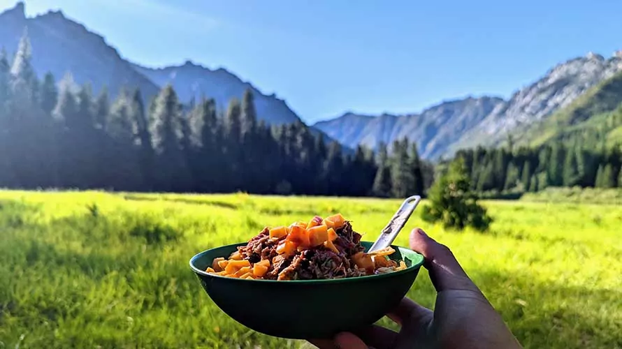 Bowl of delicious food in front of meadow in the Trinity Alps, California